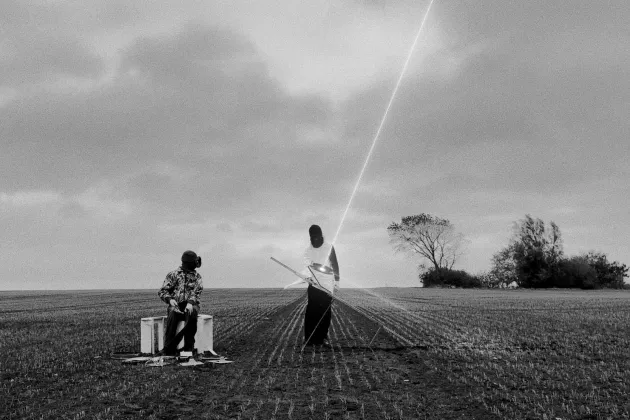 Two alienlike figures playing with a lightbeam. Photo.