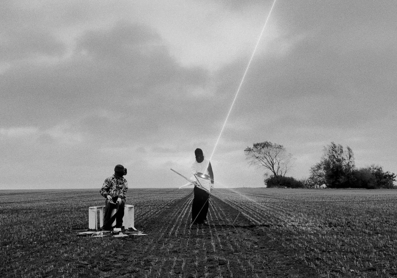 Two alienlike figures playing with a lightbeam. Photo.