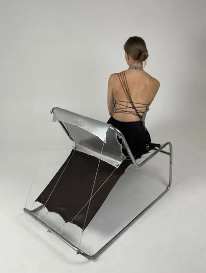 Woman sitting on armchair. Her back is visible. Photo.