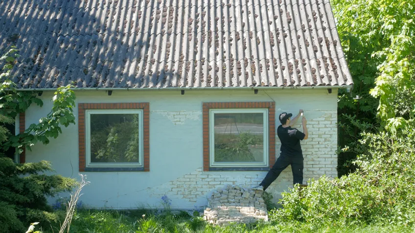 Man painting an abandoned house. Photo.